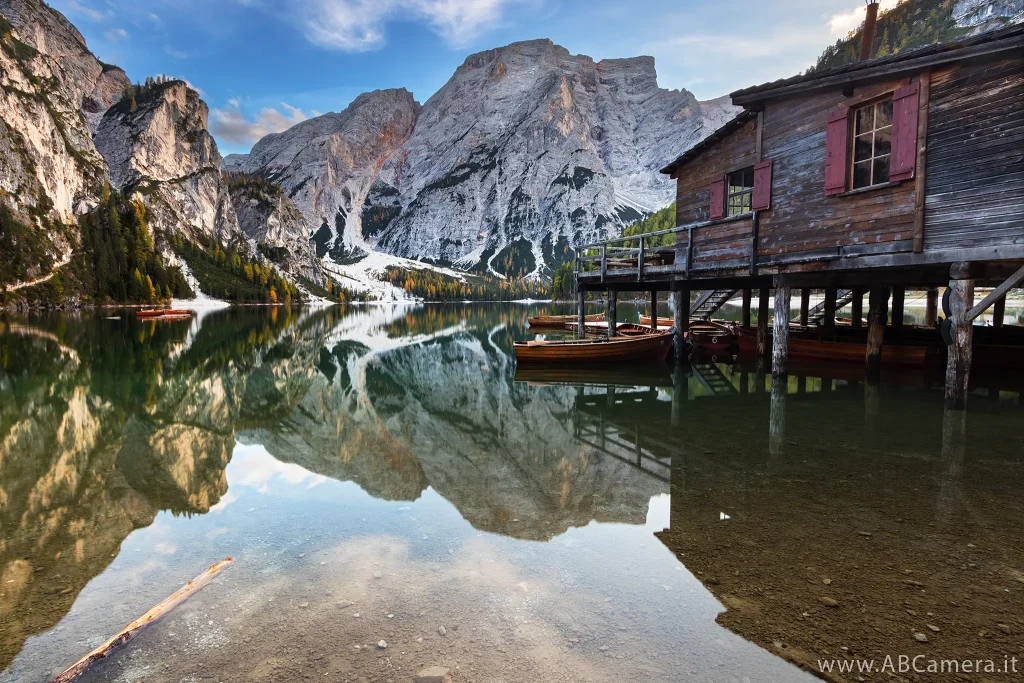 fotografia di un paesaggio naturale con elementi umani: un lago alpino con barchette di legno