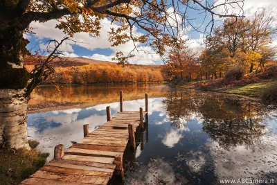 fotografia di un paesaggio naturale ripresa durante l'autunno con un grandangolo: un laghetto di montagna con pittoresco pontile in primo piano